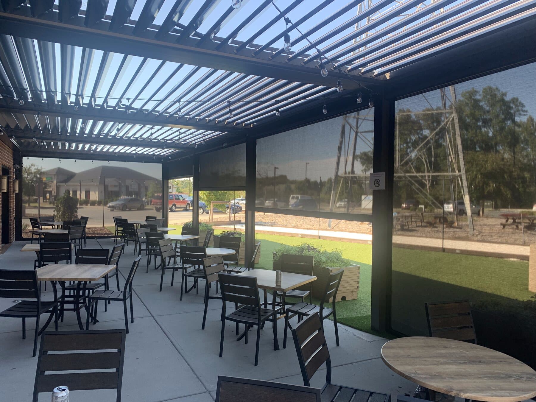 Large motorized screens enclosing a covered restaurant patio